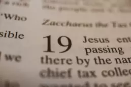 Close-up of an open Bible showing verse number 19, highlighting scripture text about Jesus and faith