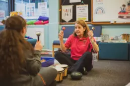 Play therapist smiling while supporting a child during an interactive play activity.