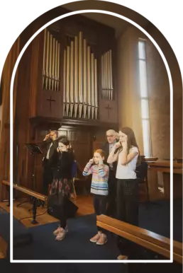 Children and adults taking part in worship during a Sunday service at Derryvolgie Church, Lisburn, with the church organ visible behind them
