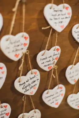 Handmade ceramic heart decorations with inspirational messages hanging at a craft stall