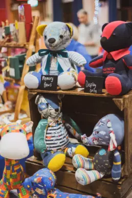 Handcrafted memory bears and soft toys displayed at a children’s gift stall in Derryvolgie Hall